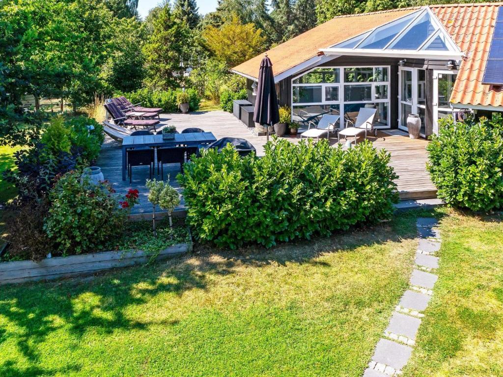 a house with a wooden deck with chairs and an umbrella at 8 person holiday home in Gilleleje in Gilleleje