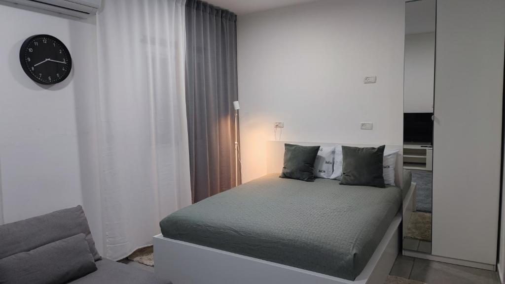 ein Schlafzimmer mit einem Bett und einer Uhr an der Wand in der Unterkunft Studio Apartment 12 Minutes from Bahai's garden in Haifa