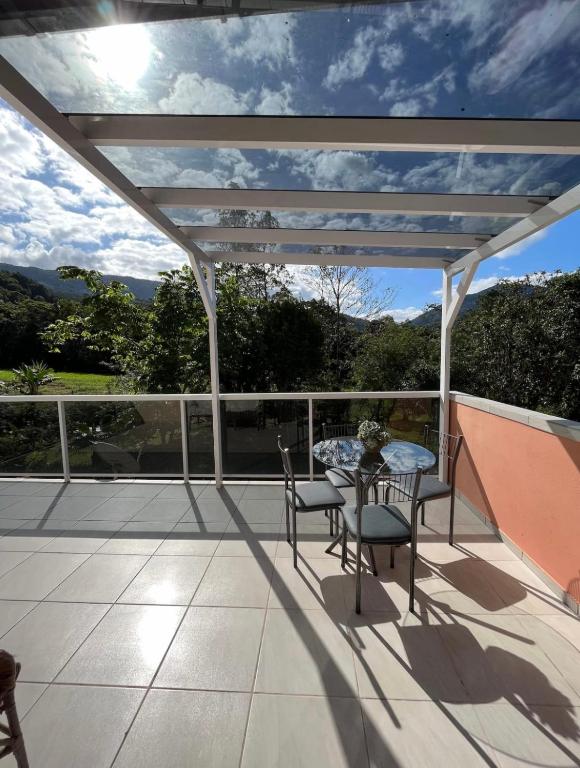 eine Terrasse mit einem Tisch und Stühlen auf dem Balkon in der Unterkunft Loft com linda vista na Rota do Enxaimel in Pomerode