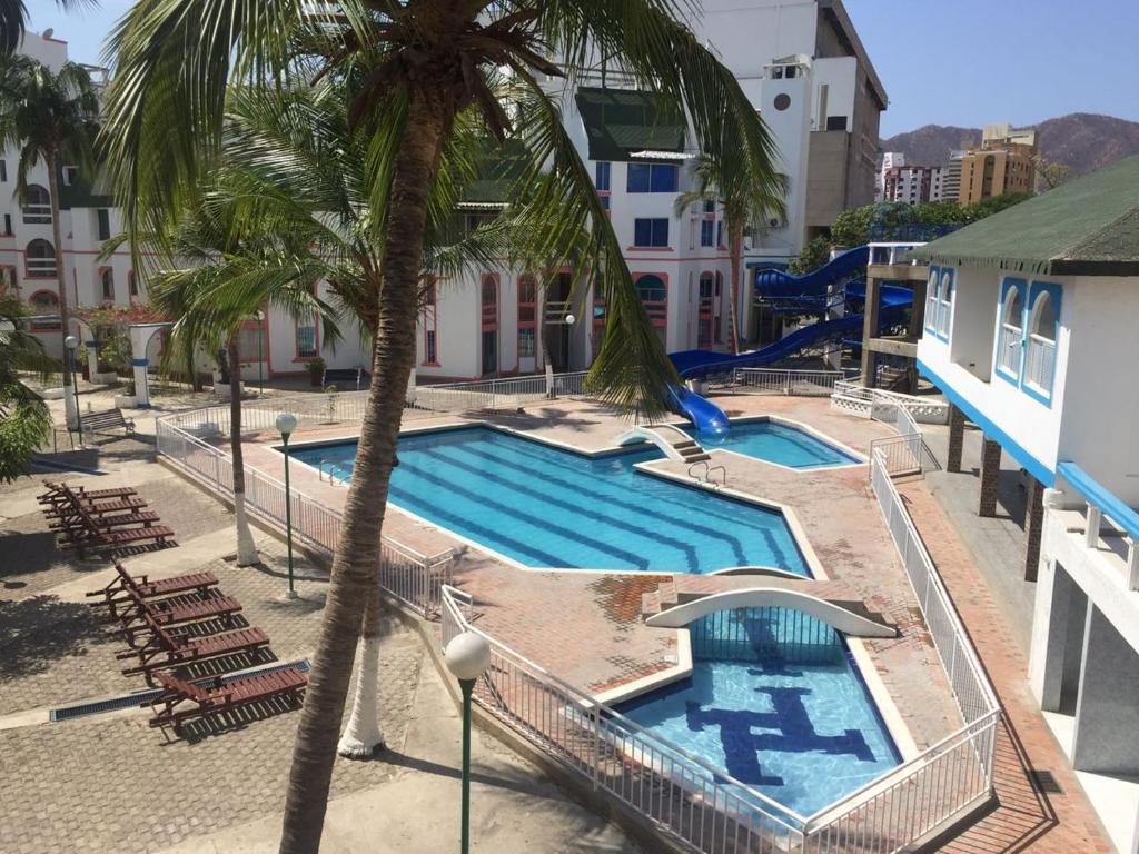 una piscina con una palmera y un tobogán en Apartamentos Playa rodadero, en Santa Marta
