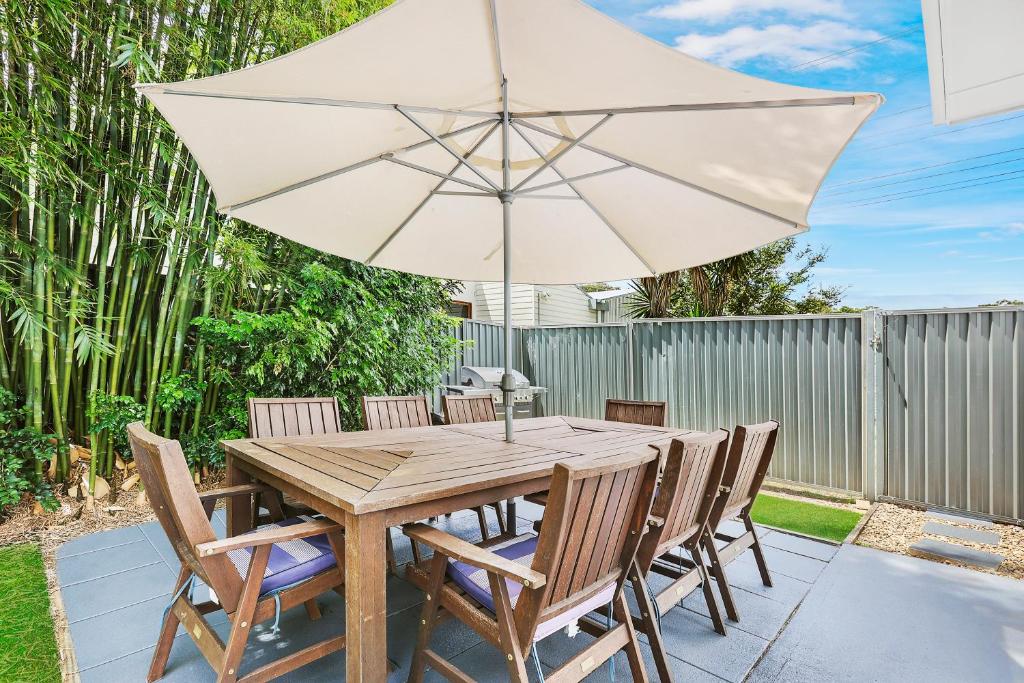a wooden table with chairs and an umbrella at Ultimate Burleigh Beach House Family Retreat! - 5 BEDROOMS in Gold Coast