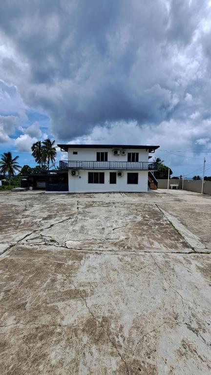 a white building with palm trees in front of it at Meadroad homestay Tour&Transfer 1 bedroom in Suva