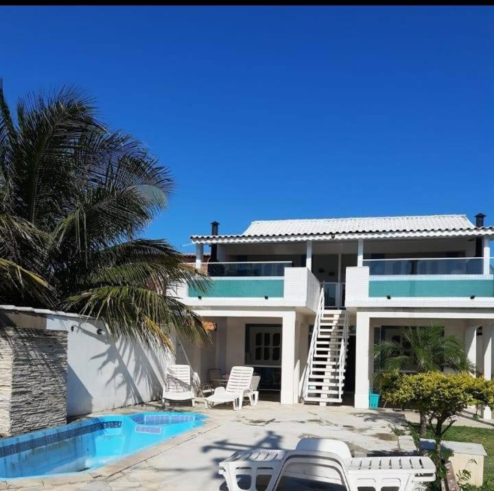uma casa com uma piscina e uma palmeira em All- Suítes Praia Arraial -FIGUEIRA em Arraial do Cabo
