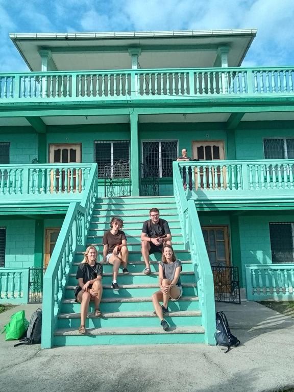 a group of people sitting on the stairs of a house at Hostel Casa Verde, Tela Atlantida. in Tela