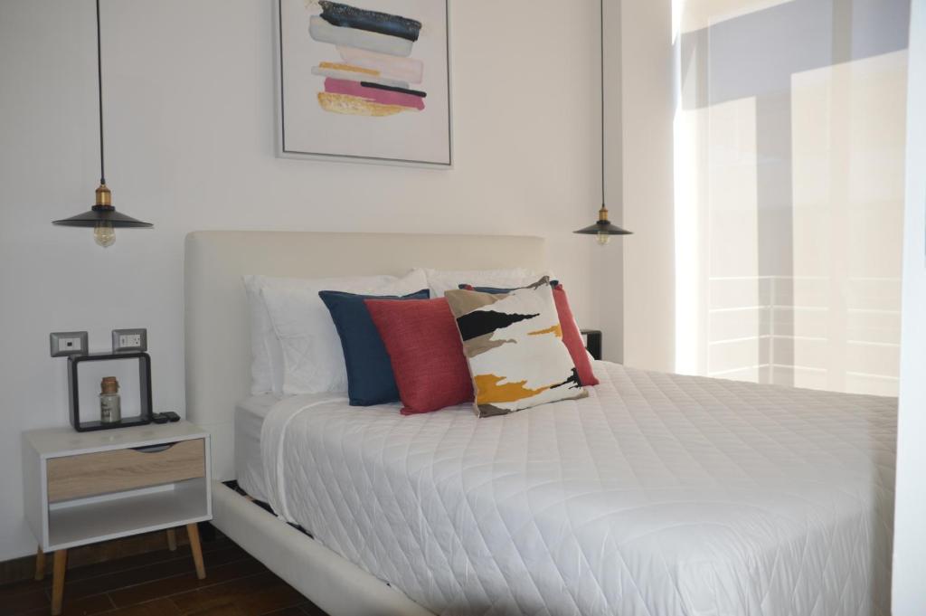 Un dormitorio con una cama blanca con almohadas. en Cozy Stays Cayala Apartments 602, en Guatemala