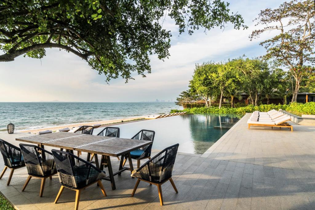 a dining table and chairs next to a swimming pool at Andaz Pattaya Jomtien Beach, a Concept by Hyatt in Na Jomtien