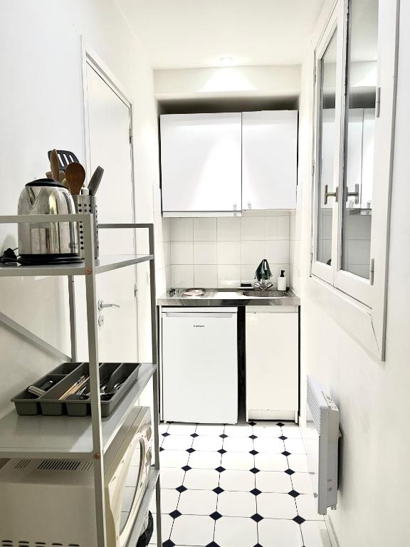 a kitchen with white cabinets and a black and white tile floor at [New] Eiffel tower view studio &#47; Paris Étoile in Paris