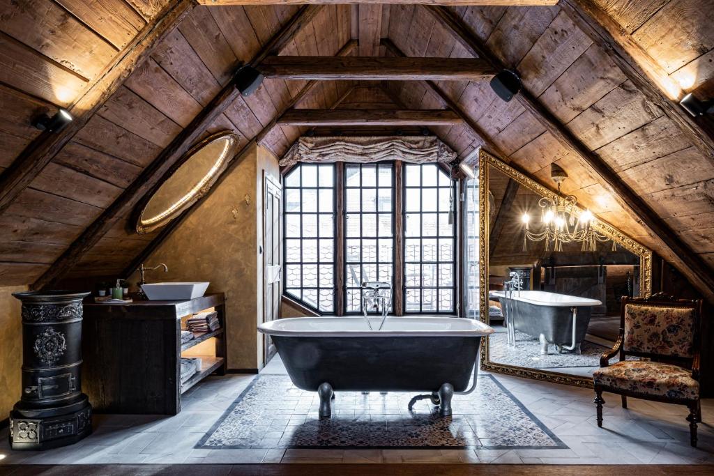 an attic bathroom with a tub and a sink at Atrium Konak in Novi Sad