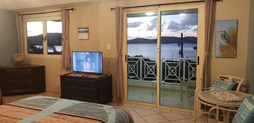 a bedroom with a bed and a television and a balcony at EliMar Bay View Studio in Culebra