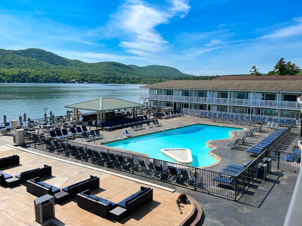 a swimming pool at a resort with chairs and a lake at The Georgian Resort in Lake George