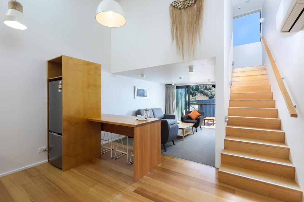 a kitchen and living room with a staircase in a house at Kaiteriteri Reserve Apartments in Kaiteriteri