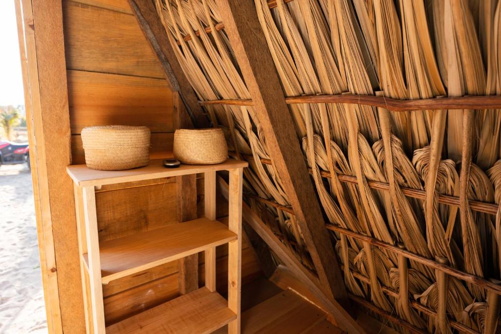 Habitación con pared de madera, estante y 2 cestas. en Nattivo Ecoglamping en La Sabrosa