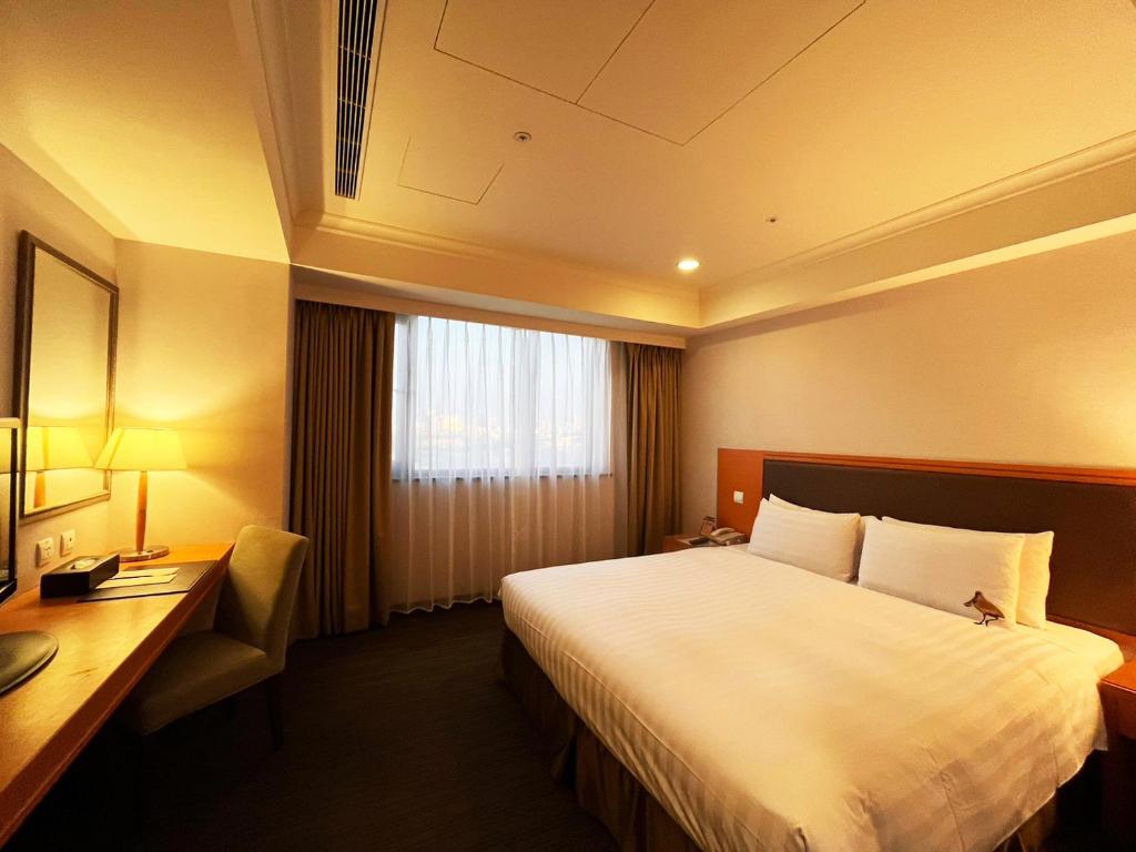 a hotel room with a large bed and a desk at Fuward Hotel Tainan in Tainan