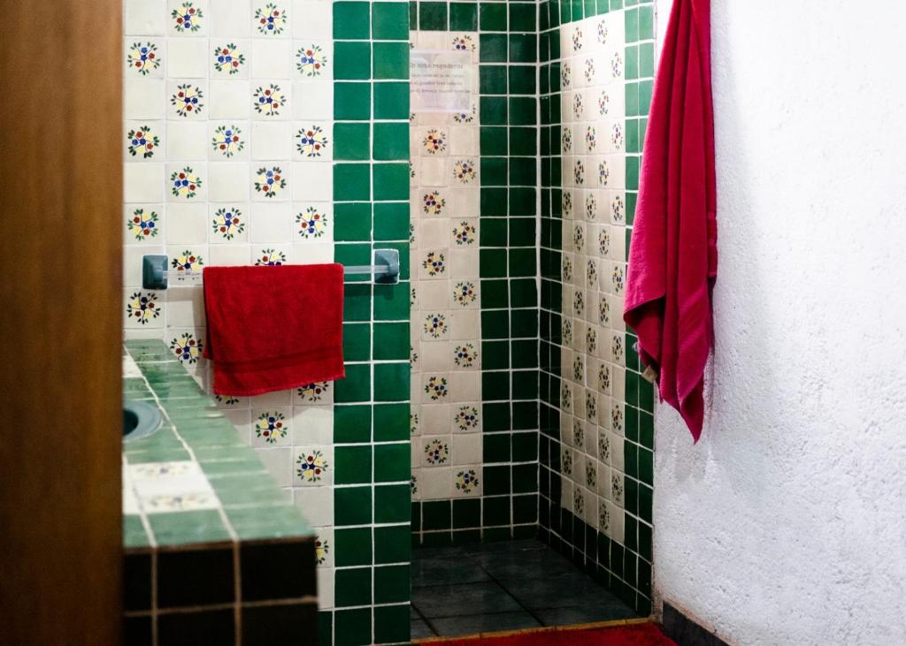 uma casa de banho com azulejos verdes e brancos e uma toalha vermelha em Hostal Tribu Malinalco em Malinalco