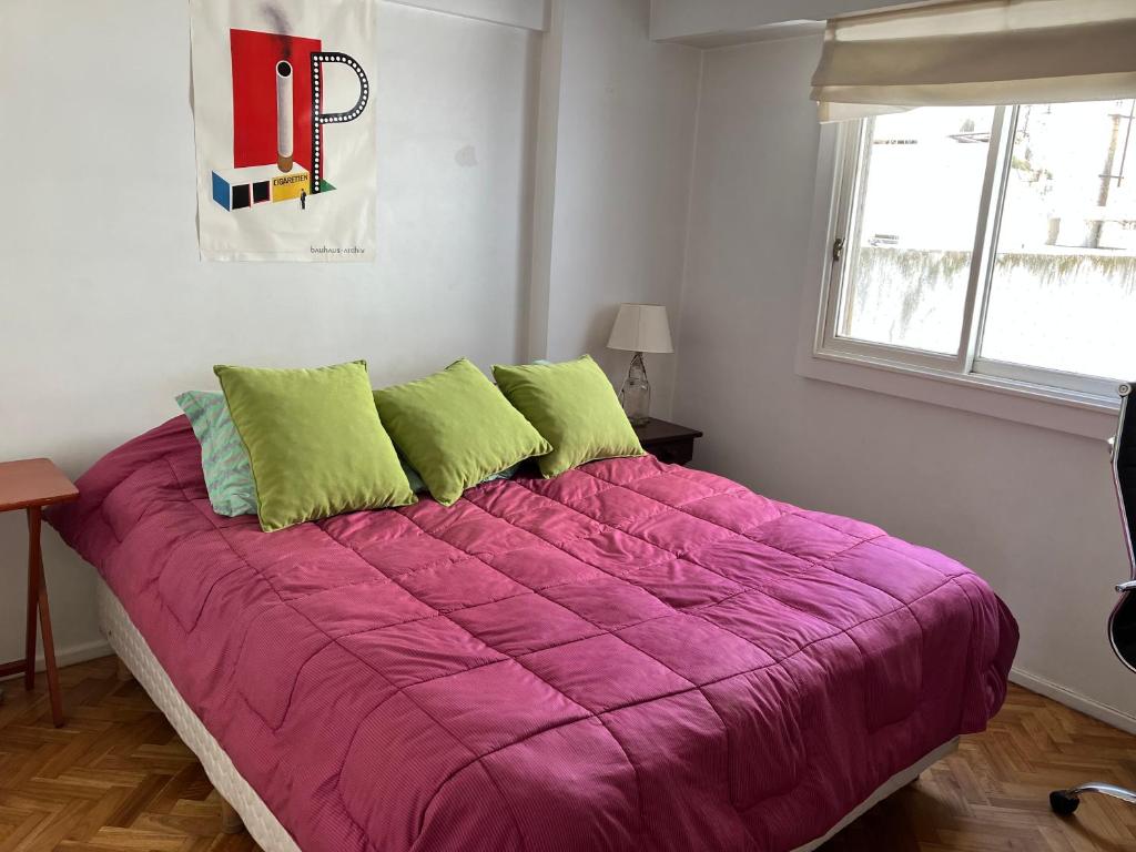Un dormitorio con una gran cama púrpura con almohadas verdes en Habitación individual en departamento compartido, barrio Recoleta en Buenos Aires