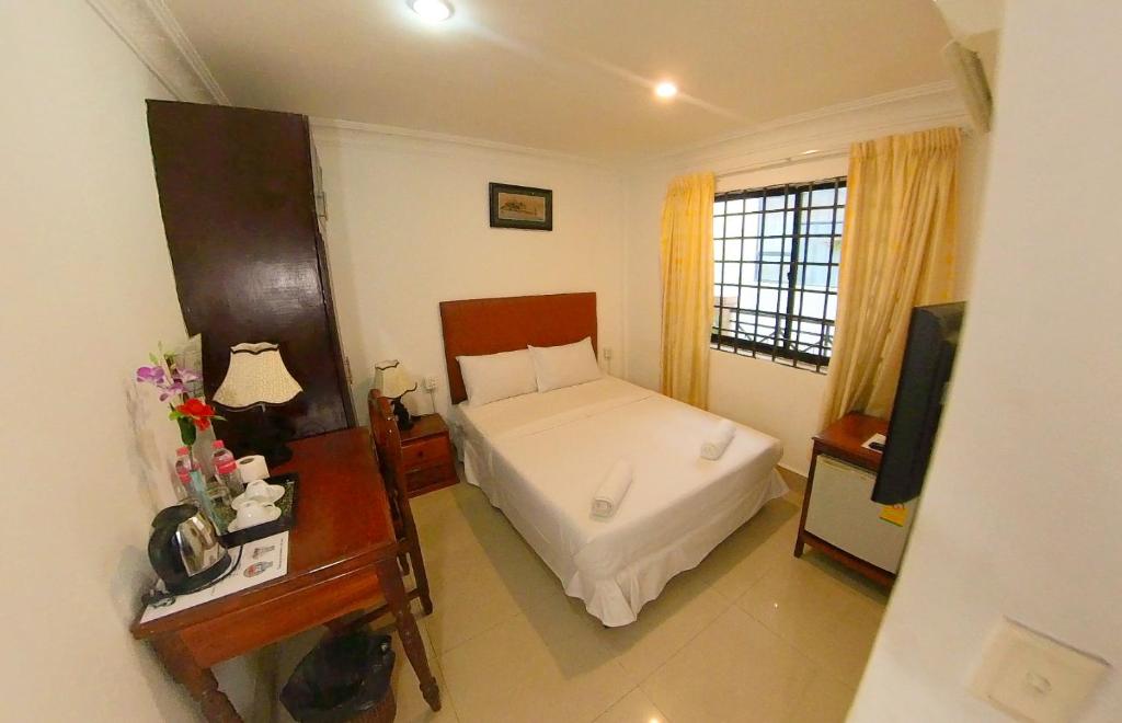 金邊的住宿－Riverside Hotel Phnom Penh，一间卧室配有一张床、一张书桌和一台电视
