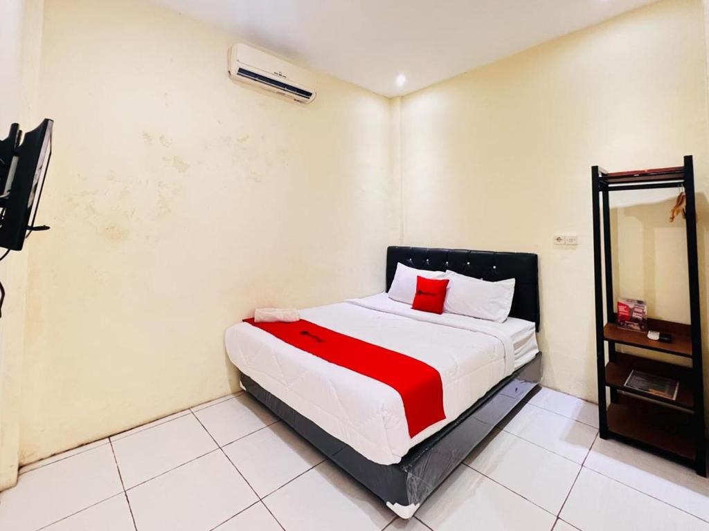 a bedroom with a bed with a red blanket and a mirror at RedDoorz near Alun Alun Sidoarjo in Sidoarjo