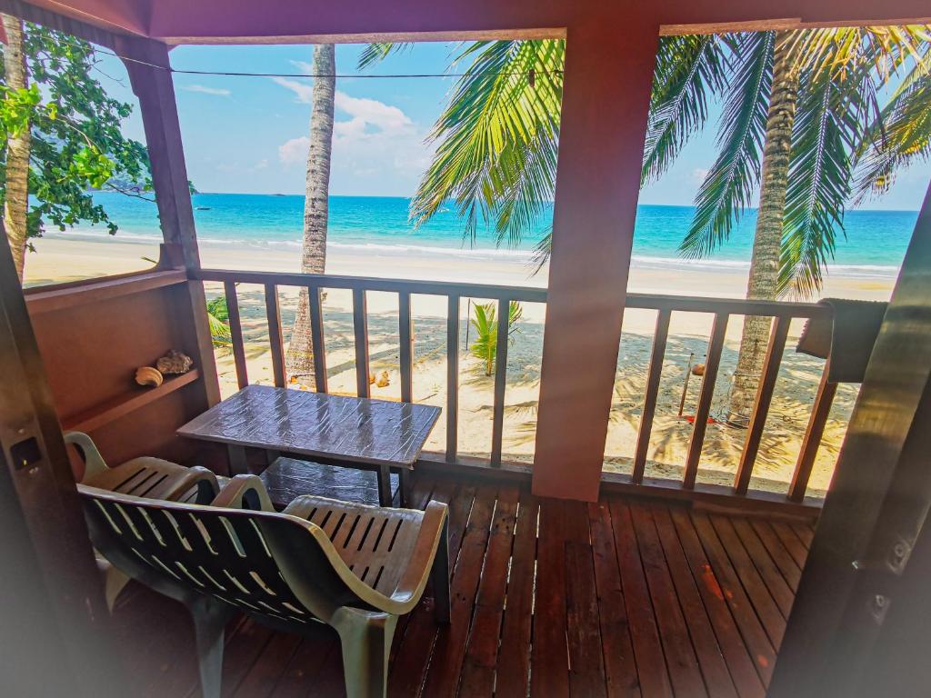 - une terrasse couverte avec une table et des chaises ainsi qu'une plage dans l'établissement Permata Beach Chalet, à Kampong Juara