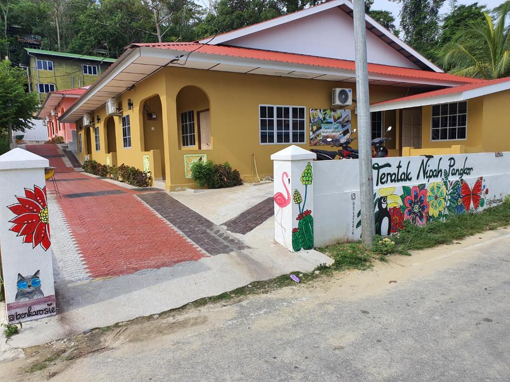 a yellow building with graffiti on it next to a street at Teratak Nipah Homestay Teluk Nipah Pangkor in Pangkor