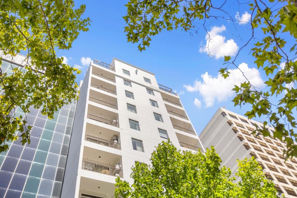un edificio alto y blanco con árboles en primer plano en Perth Cbd Retreat Victoria Ave 1br Apt en Perth