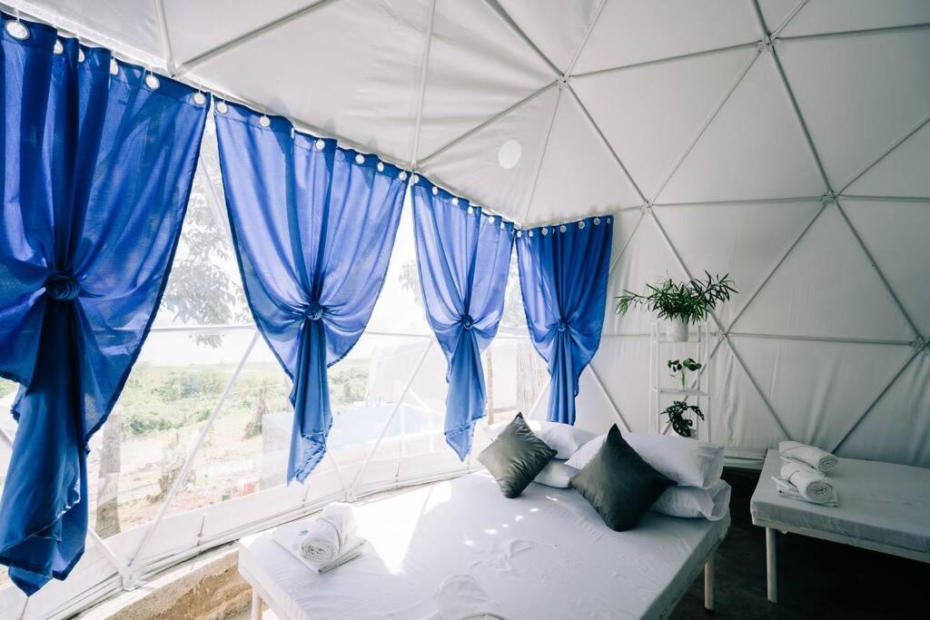 Habitación con ventana grande con cortinas azules. en Family Dome Glamping in Rizal with Private Hotspring, en Lubo