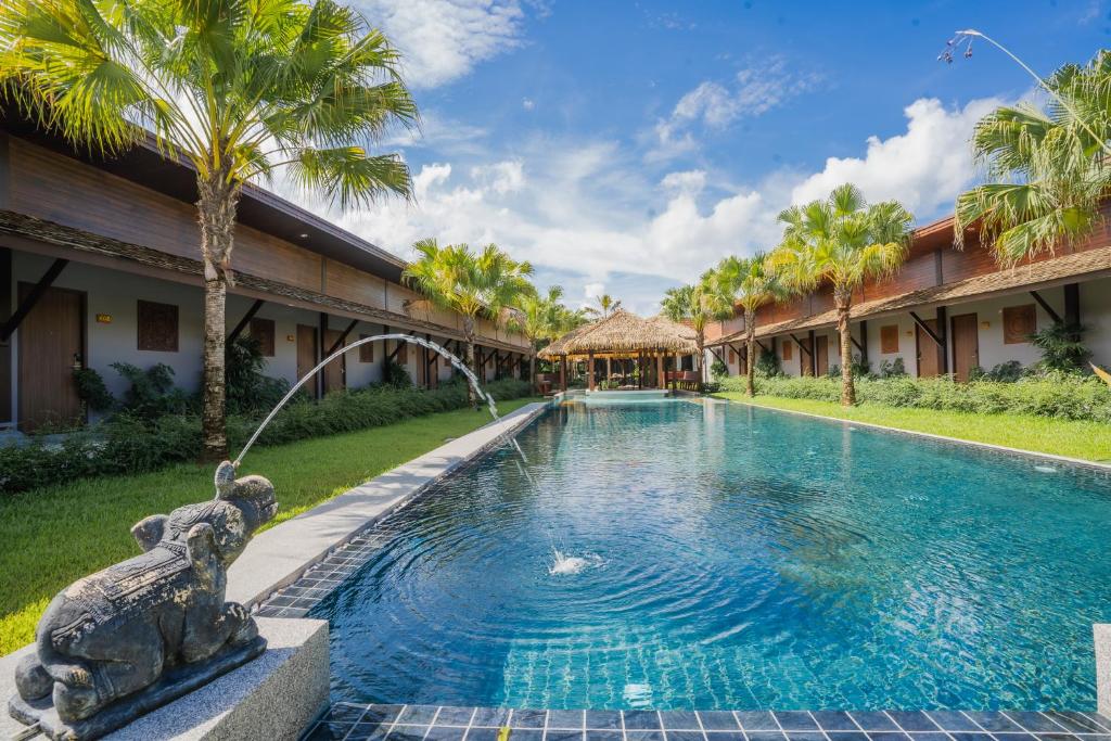 普吉市的住宿－Malabar Pool Villa Phuket，一座位于大楼旁的游泳池,设有雕像