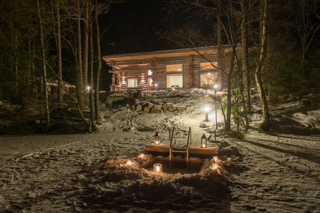 uma cabana de madeira à noite com luzes na neve em Hawkhill cottage resort em Tervalampi