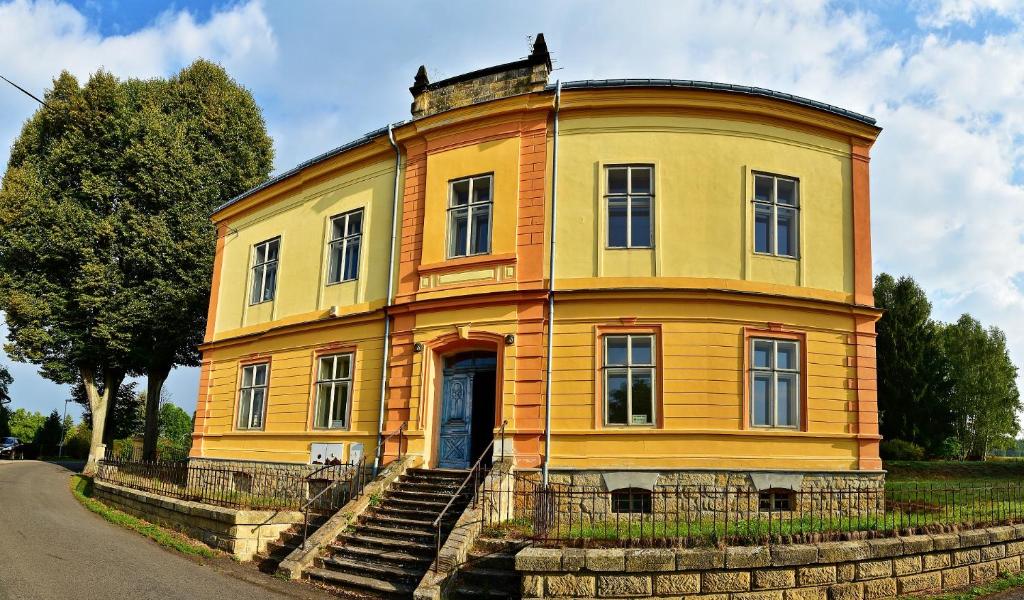 an old yellow house with stairs in front of it at Hotel Stará Škola in Mezná