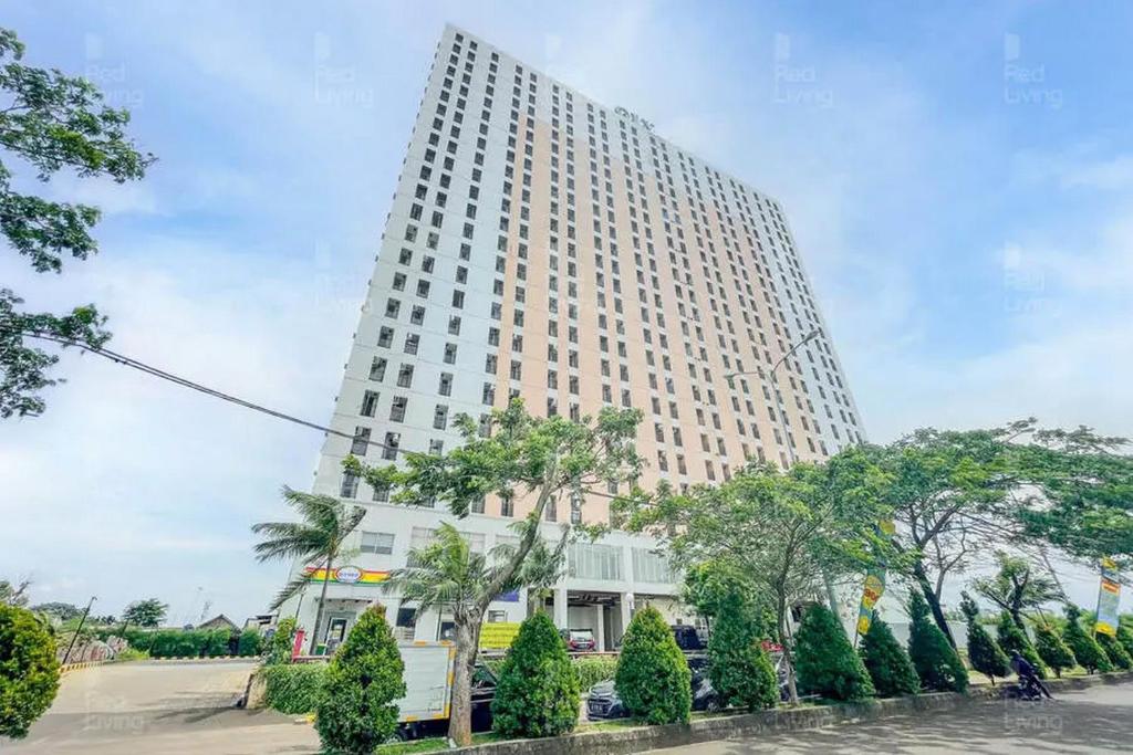 un alto edificio bianco con alberi di fronte di RedLiving Apartemen Green Lake View Cimanggis - WIN Property a Depok