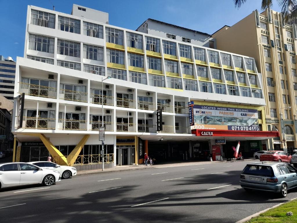 un gran edificio blanco con coches estacionados frente a él en Riviera Hotel Durban, en Durban