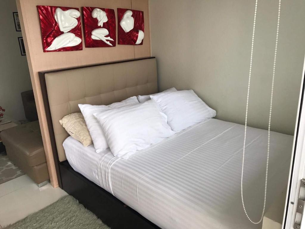 a bed with white pillows and paintings on the wall at smdc residences tagaytay tower 1 condo unit in Tagaytay