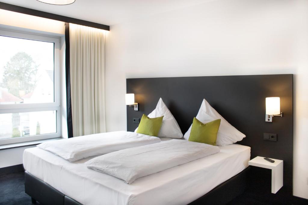 um quarto com uma grande cama branca com almofadas verdes em ING Hotel by WMM Hotels em Ingolstadt