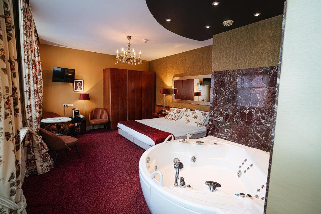 a hotel room with a tub and a bed at Hotel Johannes Vermeer Delft in Delft