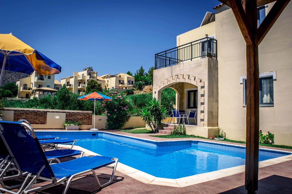 a swimming pool with two chairs and an umbrella at Nine Muses Villas - Clio Terpischori in Hersonissos