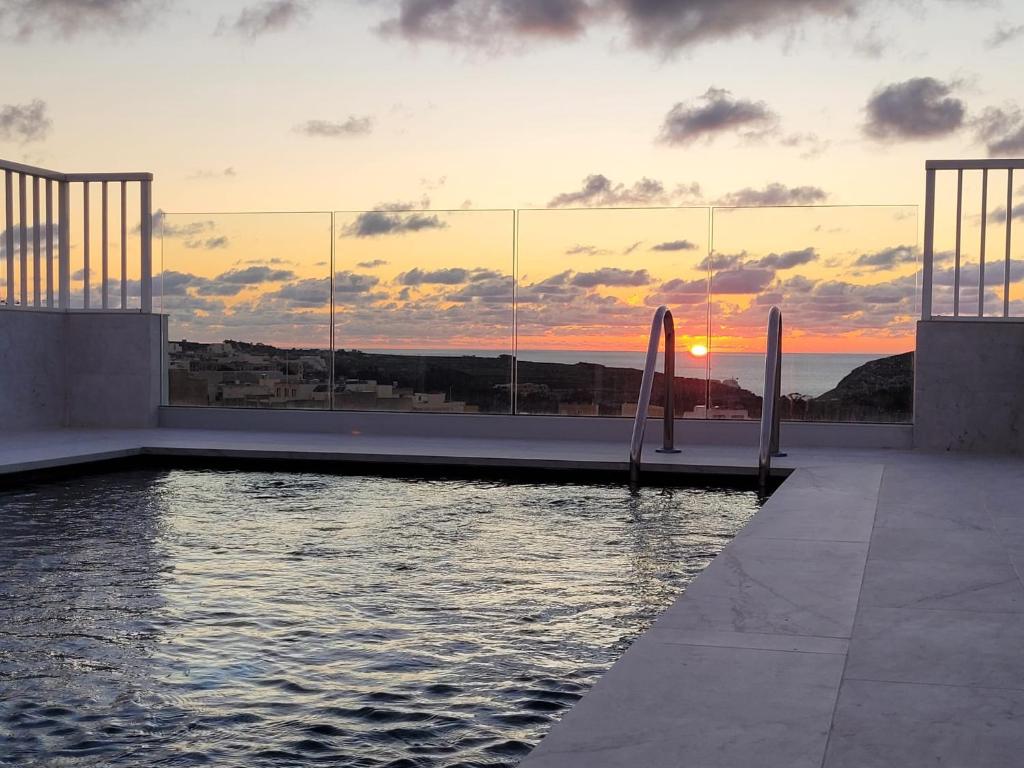 a view of the sunset from a building with a pool at Anici Crt Penthouse 4 - with private rooftop pool in Victoria