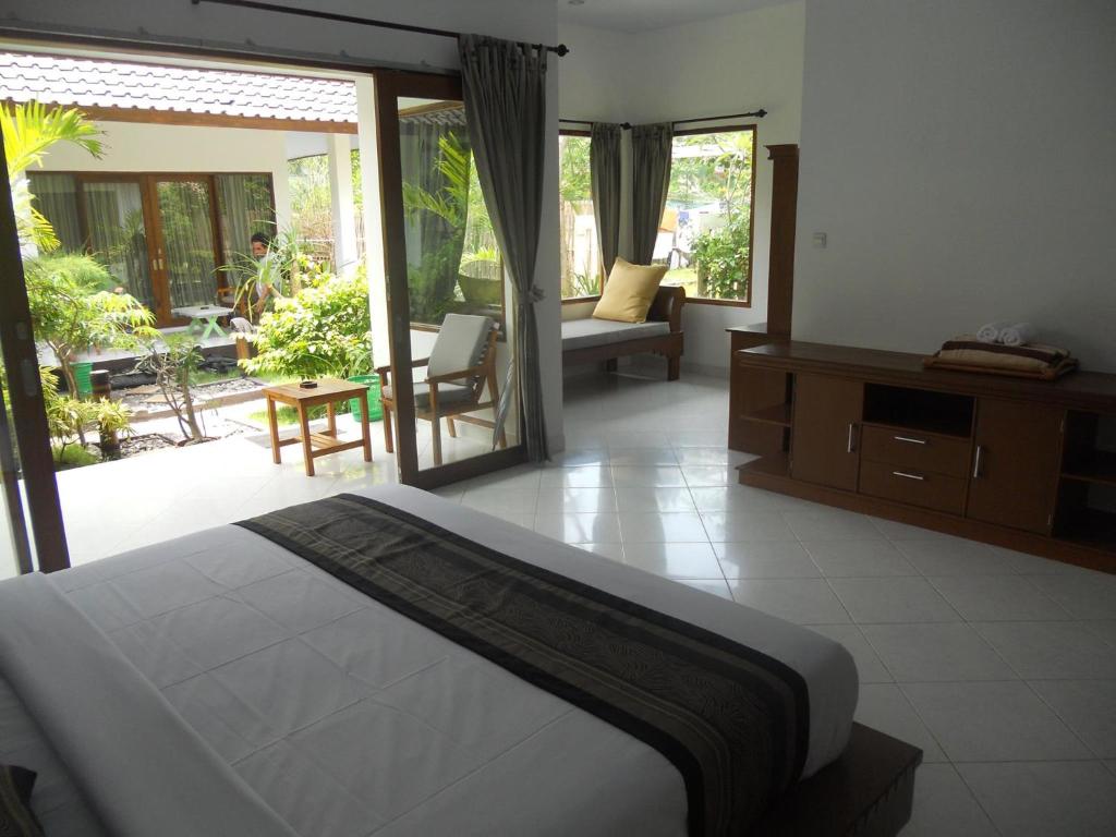 a bedroom with a bed and a living room with a patio at Gili Smile Bungalow in Gili Trawangan