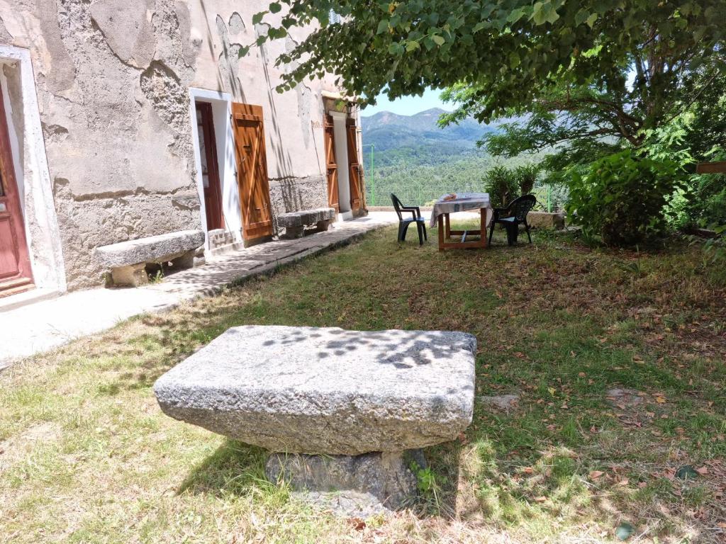 un banco de piedra sentado frente a un edificio en Andriaccia en Aullène