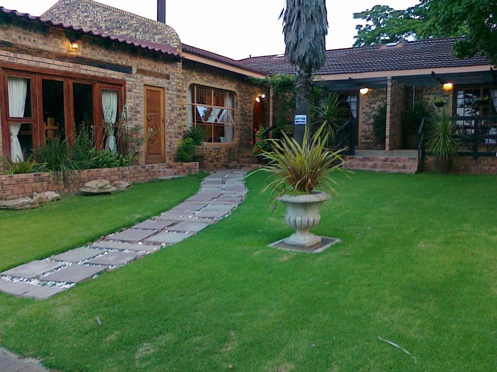 a house with a yard with a plant in the grass at Khokha Moya Guesthouse in Ermelo