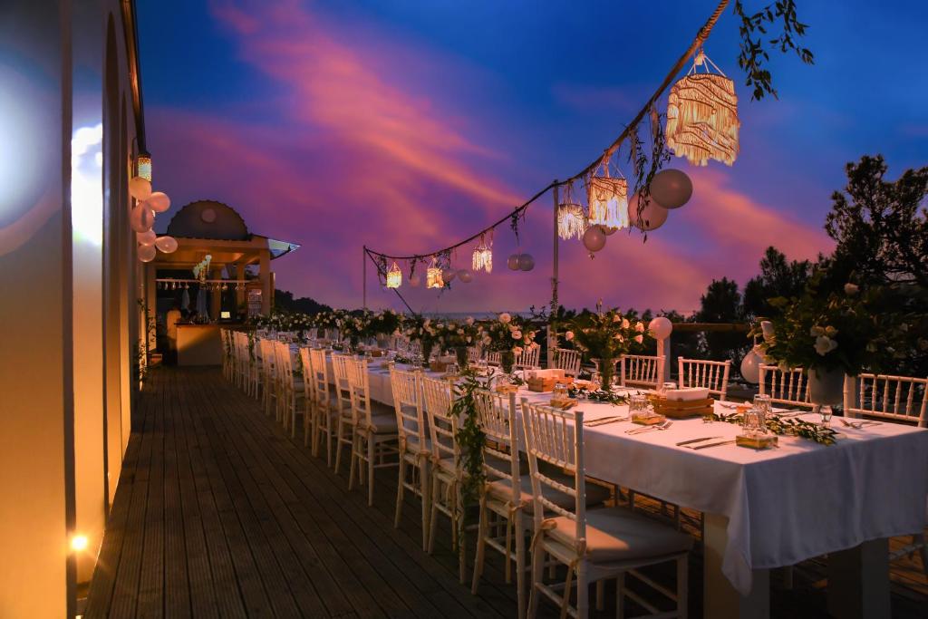 a row of tables with white chairs and lights at Zakros Hotel Lykia in Faralya