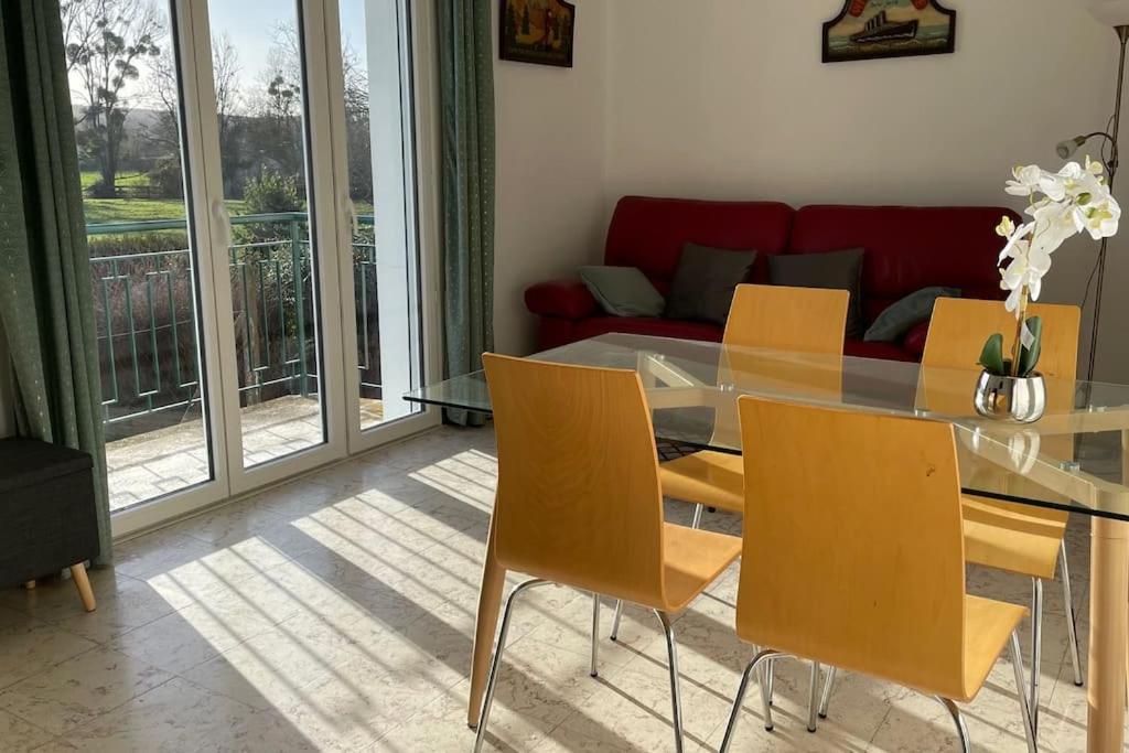 a dining room with a glass table and yellow chairs at Maison 4 personnes dans village Cœur du perche avec toutes commodités Mini 2jours in Condé-sur-Huisne