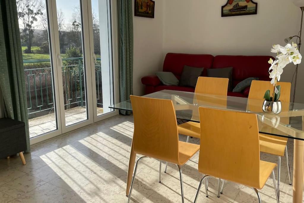a dining room with a glass table and yellow chairs at Maison 4 personnes dans village Cœur du perche avec toutes commodités Min 2 nuits in Condé-sur-Huisne
