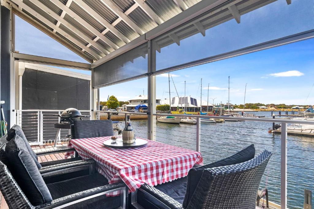 a table and chairs on a porch with a view of the water at Marina View Port Geographe with WiFi in Wonnerup
