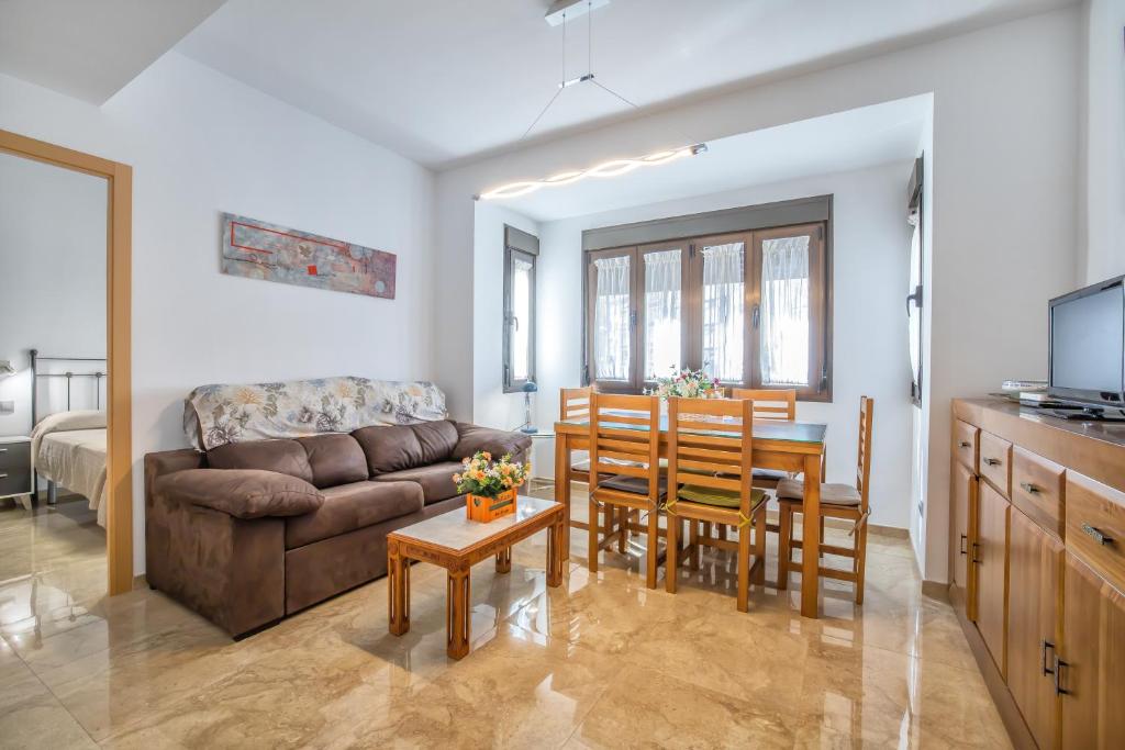 ein Wohnzimmer mit einem Sofa, einem Tisch und Stühlen in der Unterkunft Fleming, cómodo apartamento junto Mezquita y Judería in Córdoba