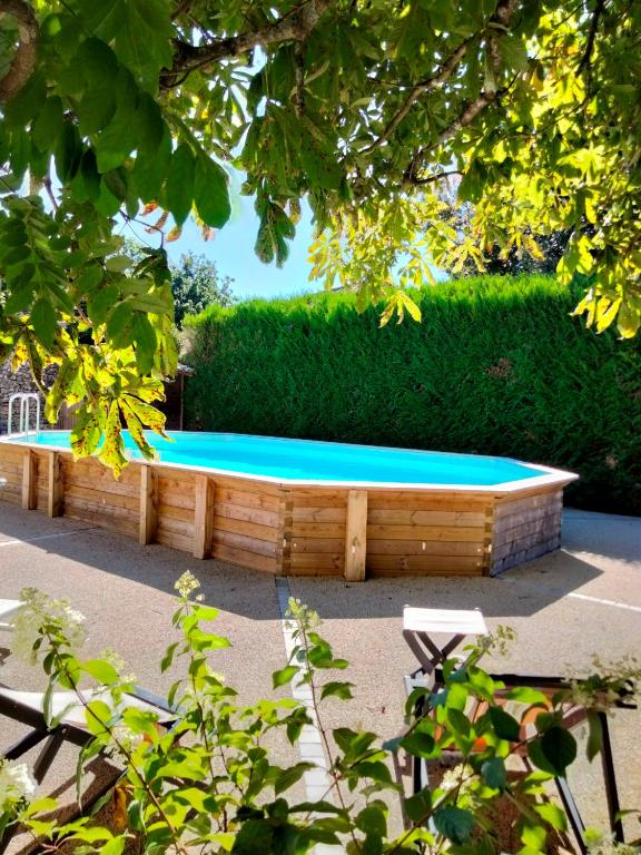 un banc en bois avec une piscine en face d'une haie dans l'établissement O 4 SAISONS DE BREILBON, à Germond