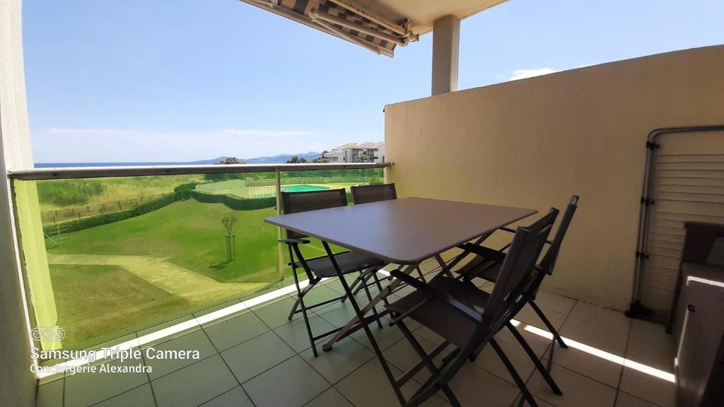 einen Tisch und Stühle in einem Zimmer mit Fenster in der Unterkunft LES GOELLETTES : vue mer et piscine in Saint-Cyprien