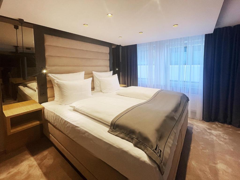 ein Schlafzimmer mit einem großen Bett mit weißen Kissen in der Unterkunft DORMERO Hotel Reutlingen in Reutlingen