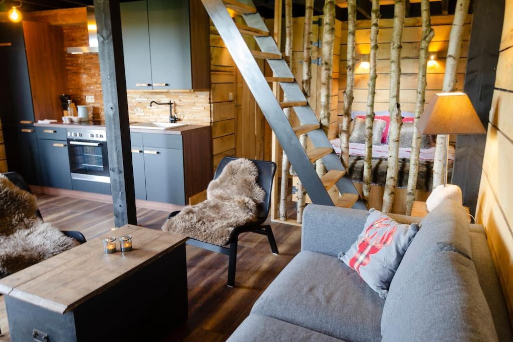 a living room with a couch and a staircase at La cabane du cerf et son sauna in Attre