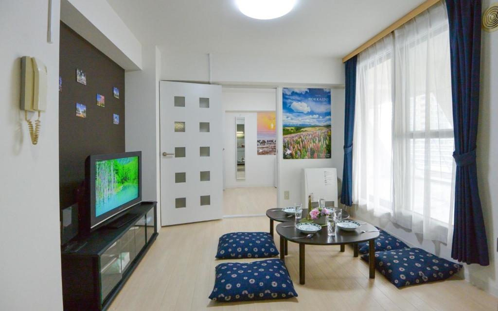 a living room with a television and a table and chairs at Carid Shiraishi In front of the station / Vacation STAY 4651 in Sapporo