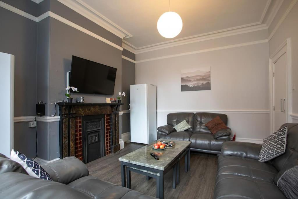 a living room with leather couches and a fireplace at Hömli*Close2City*LargeGroup*Wi-Fi* in Leicester