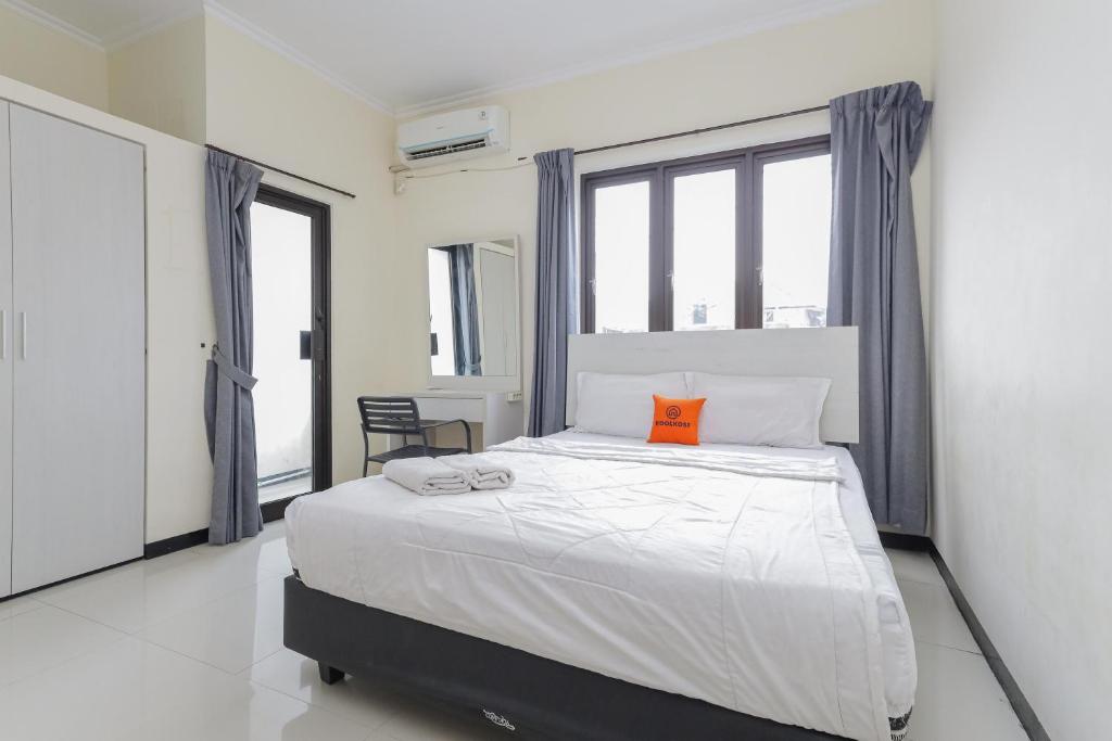 a bedroom with a large white bed with an orange pillow at KoolKost near Tunjungan Plaza in Surabaya